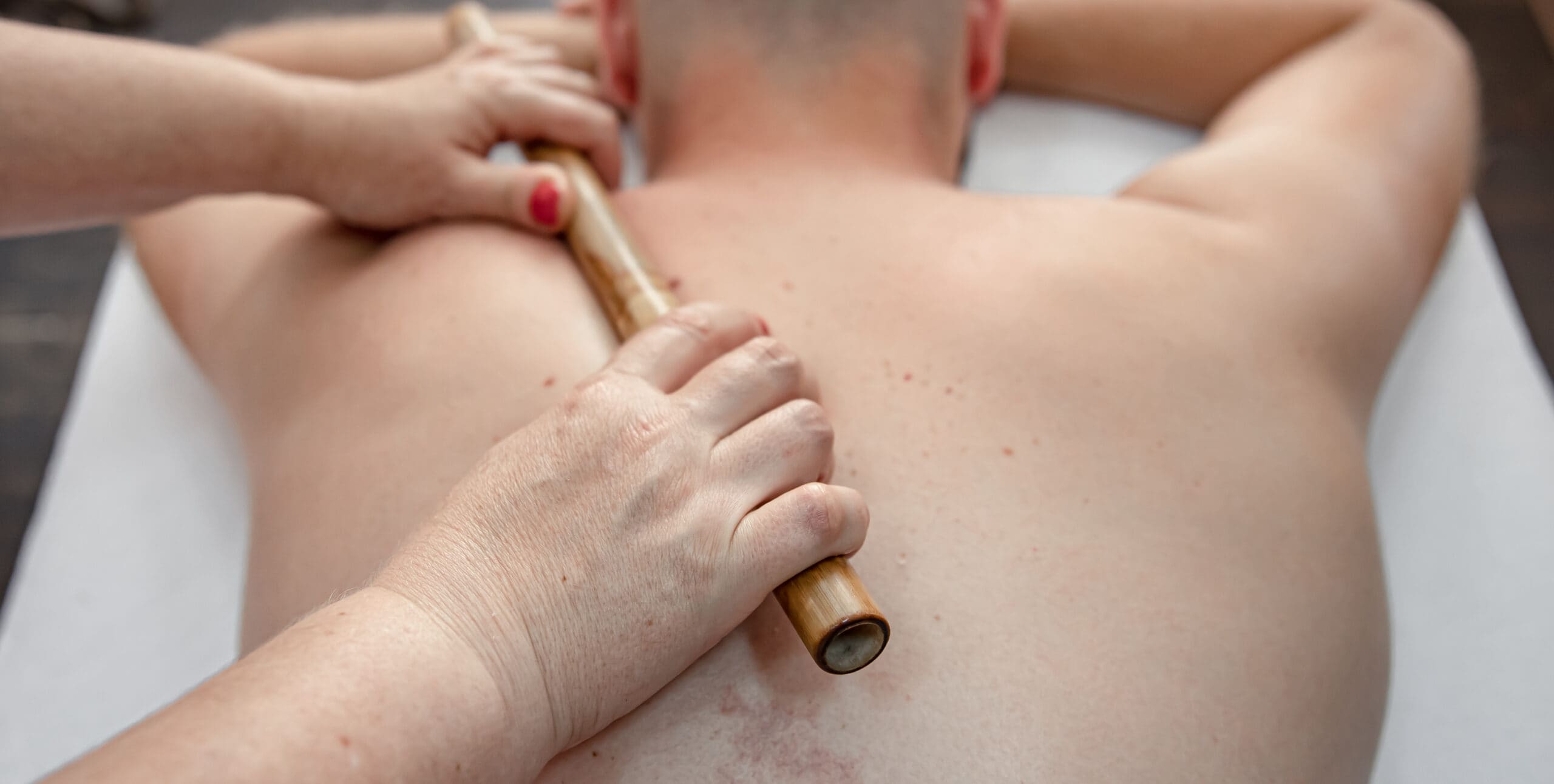 the-masseur-using-massage-bamboo-sticks-during-treatment-scaled